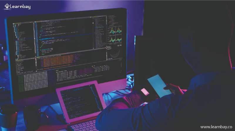 A man seated in front of a laptop is busy in coding.