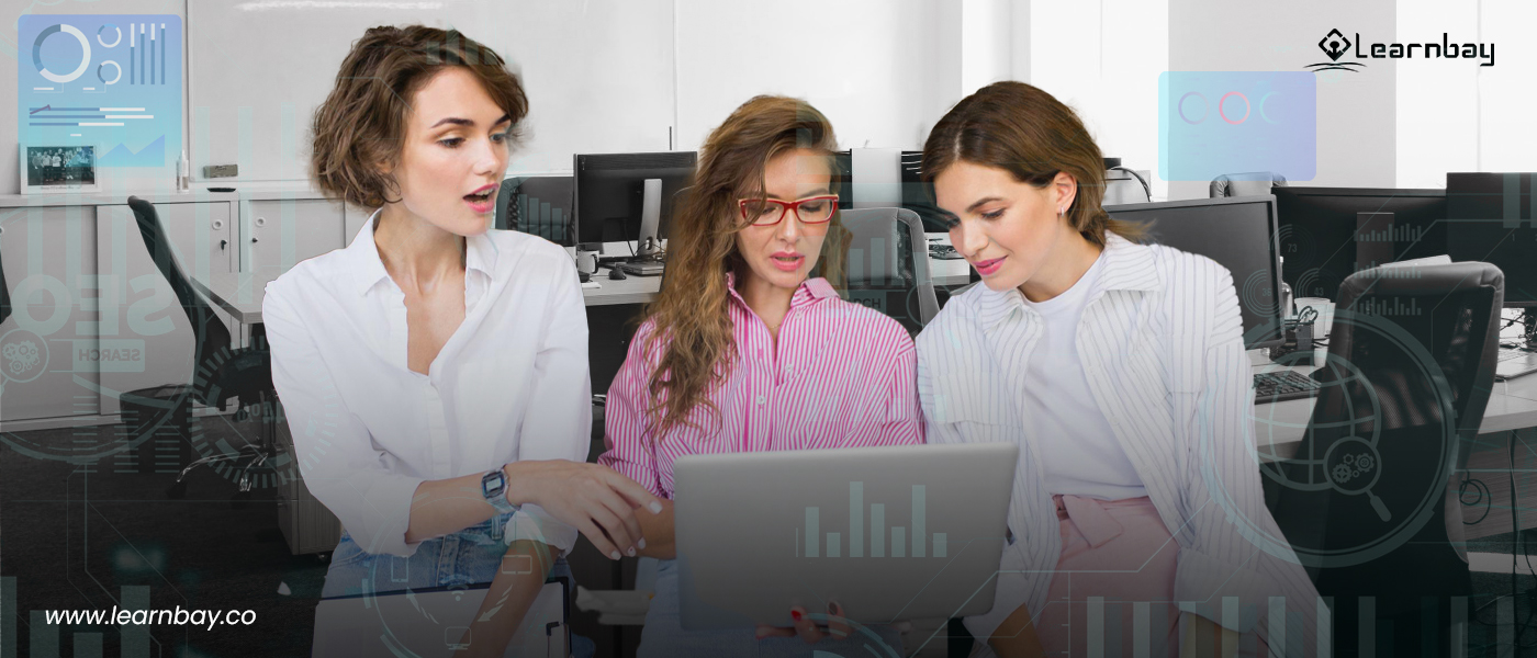 A group of female data scientists hold a laptop and are busy discussing.